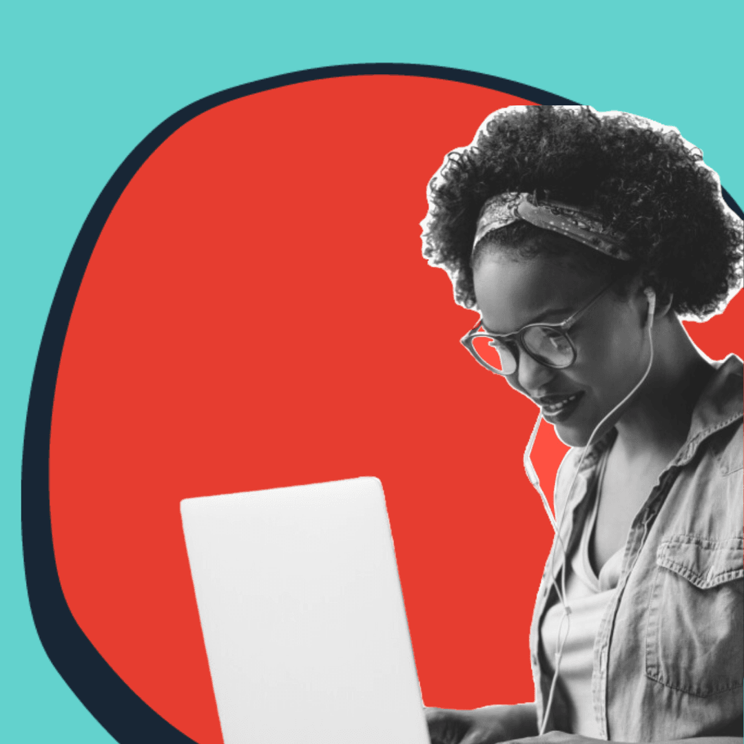 Black woman sitting at a laptop with earbuds in.